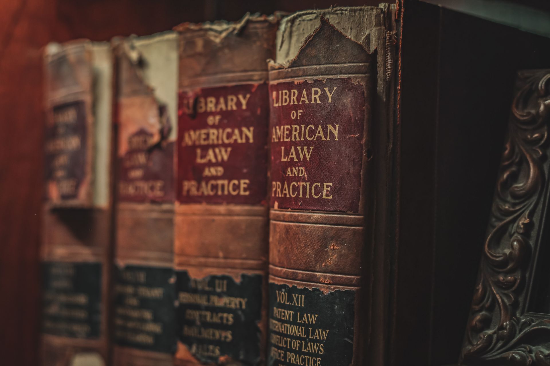 A row of old law books sitting on top of a wooden shelf.