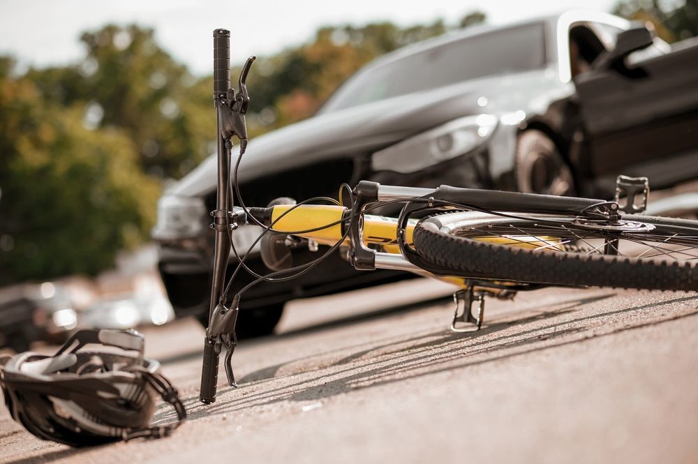 A bicycle is laying on the ground next to a car.
