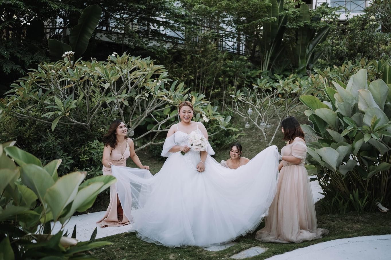 A bride and her bridesmaids are posing for a picture in a garden.