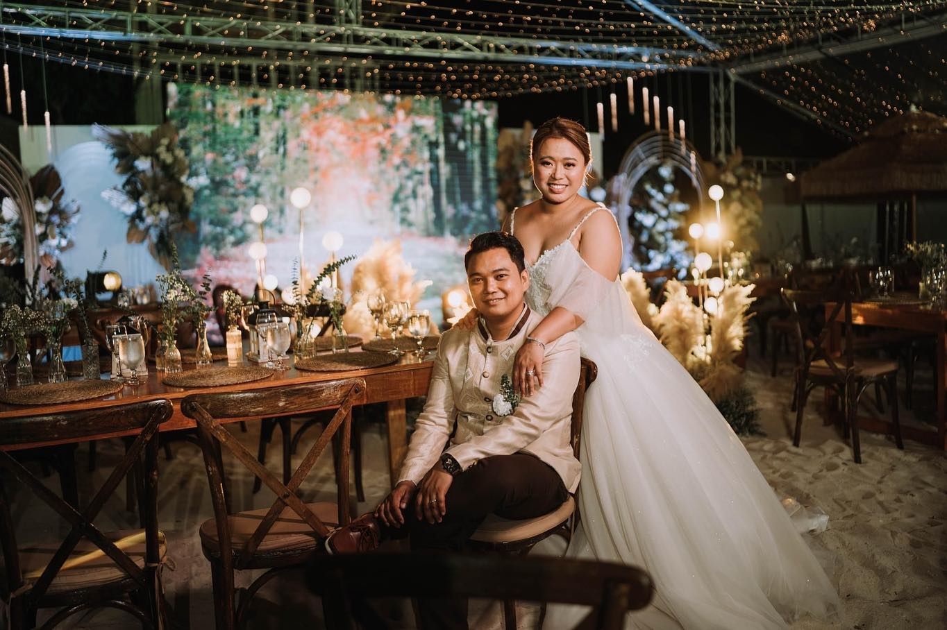 A bride and groom are posing for a picture at their wedding reception.
