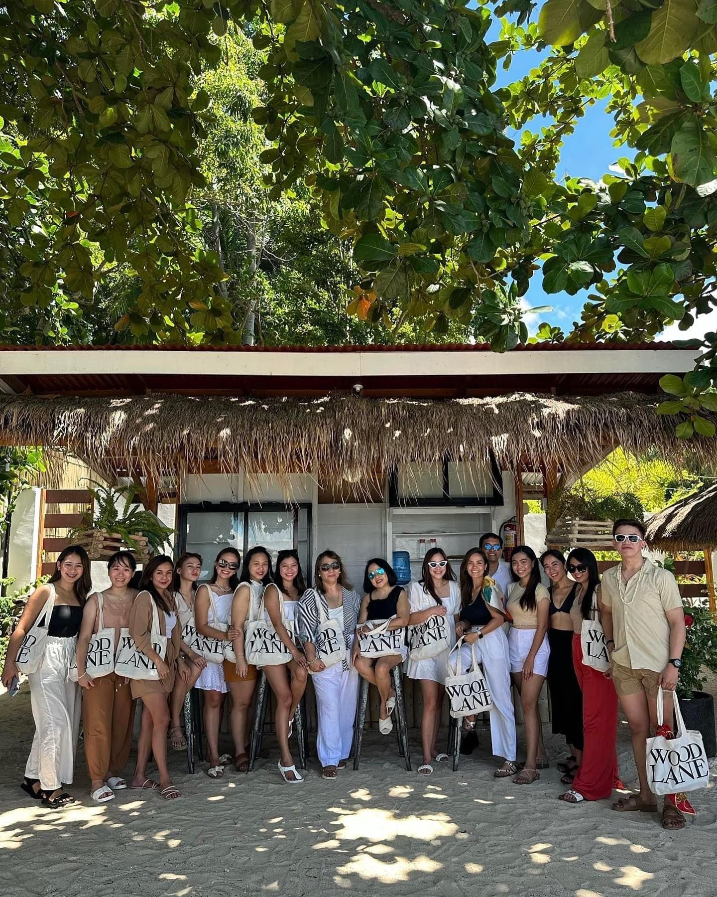 A group of people are posing for a picture in front of a thatched roof.