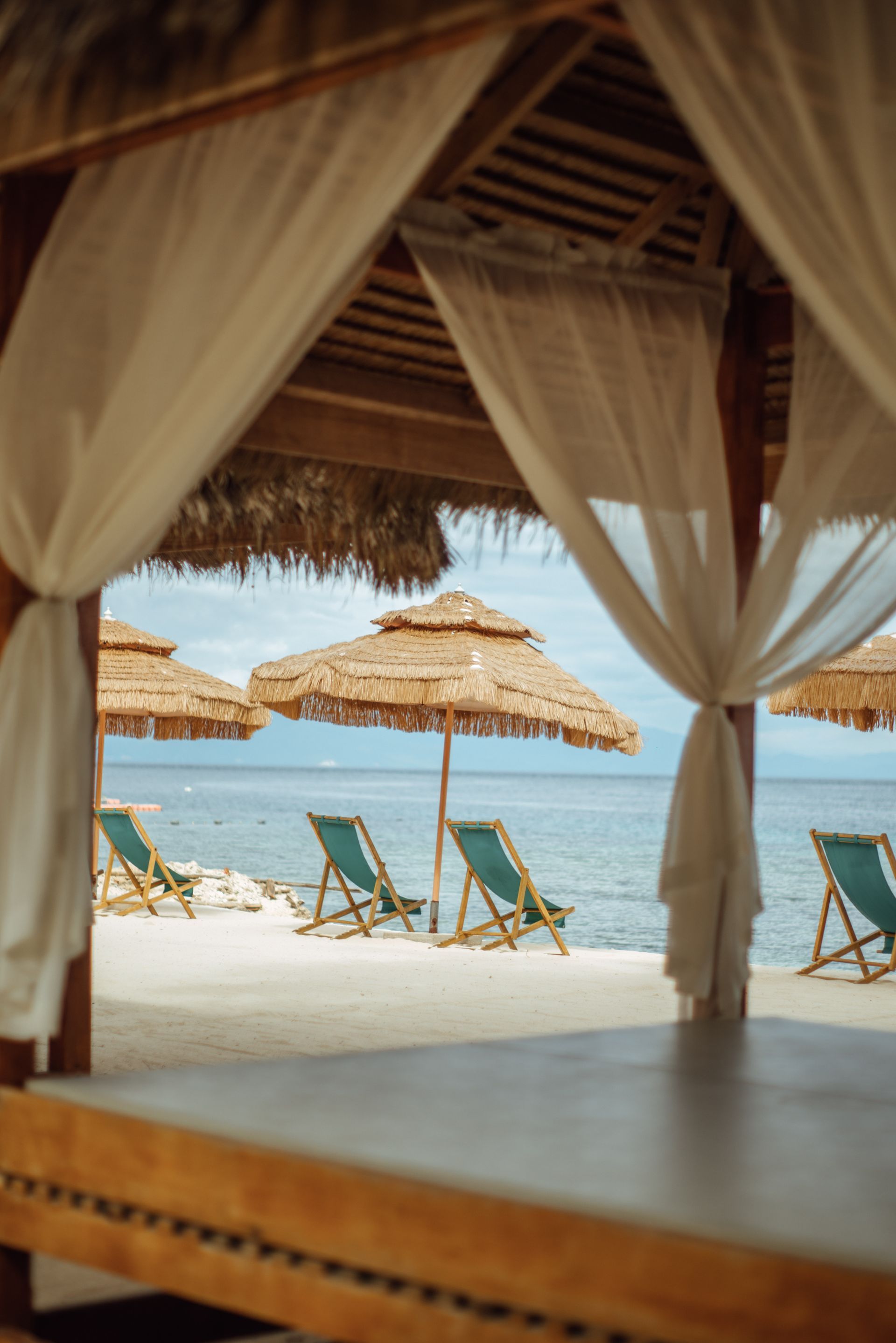 A gazebo on a beach with umbrellas and chairs
