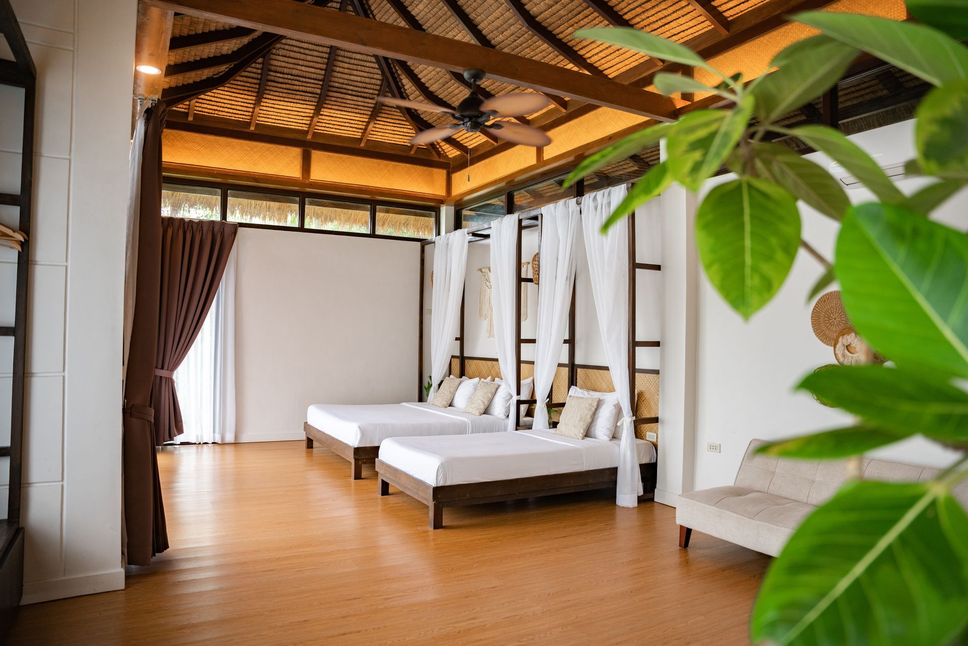 A bedroom with three beds , a couch , and a ceiling fan.