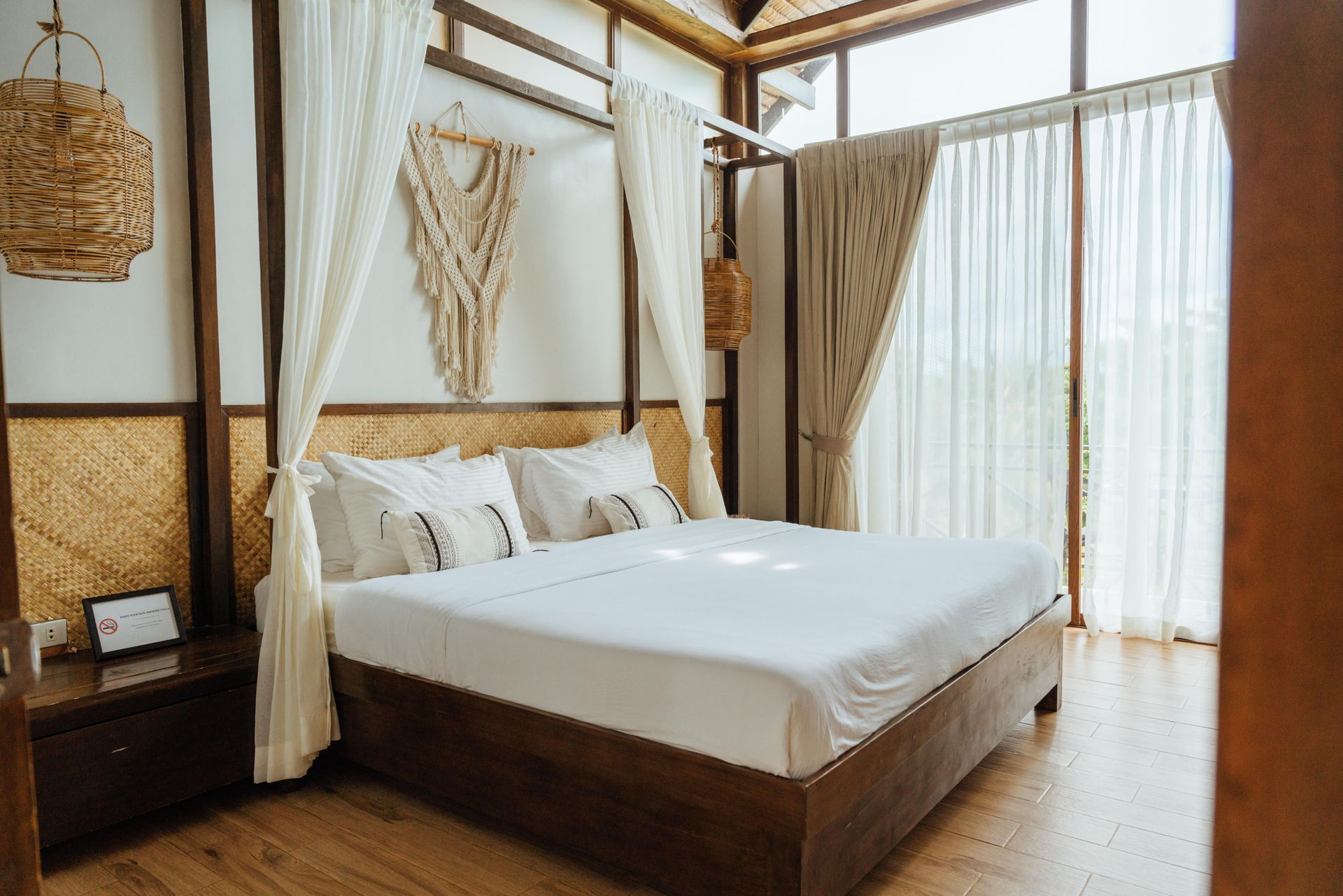 A bedroom with a canopy bed and a large window.