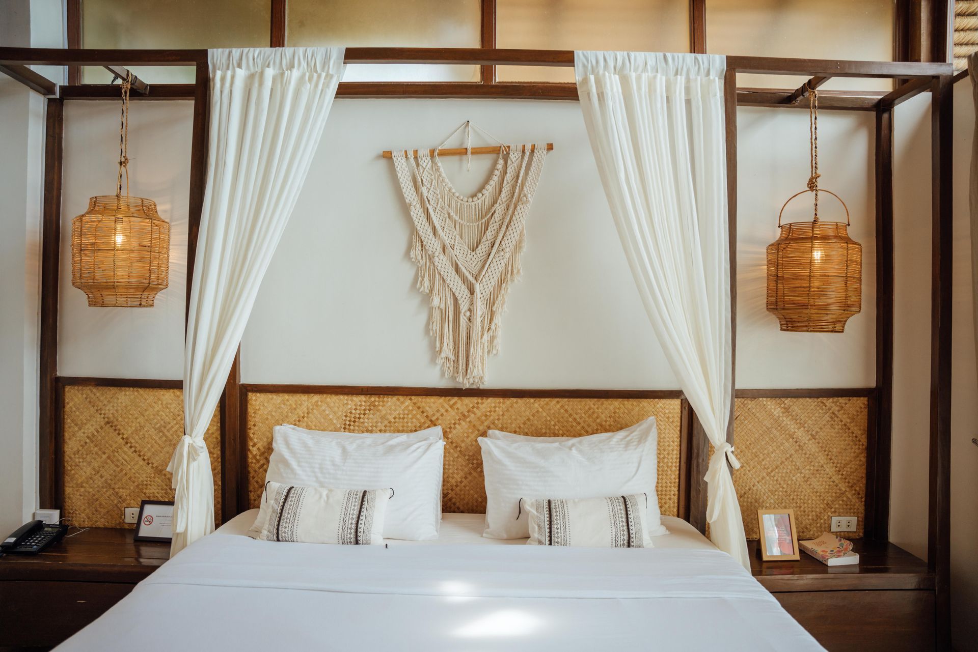 A bedroom with a canopy bed and two lanterns hanging from the ceiling.
