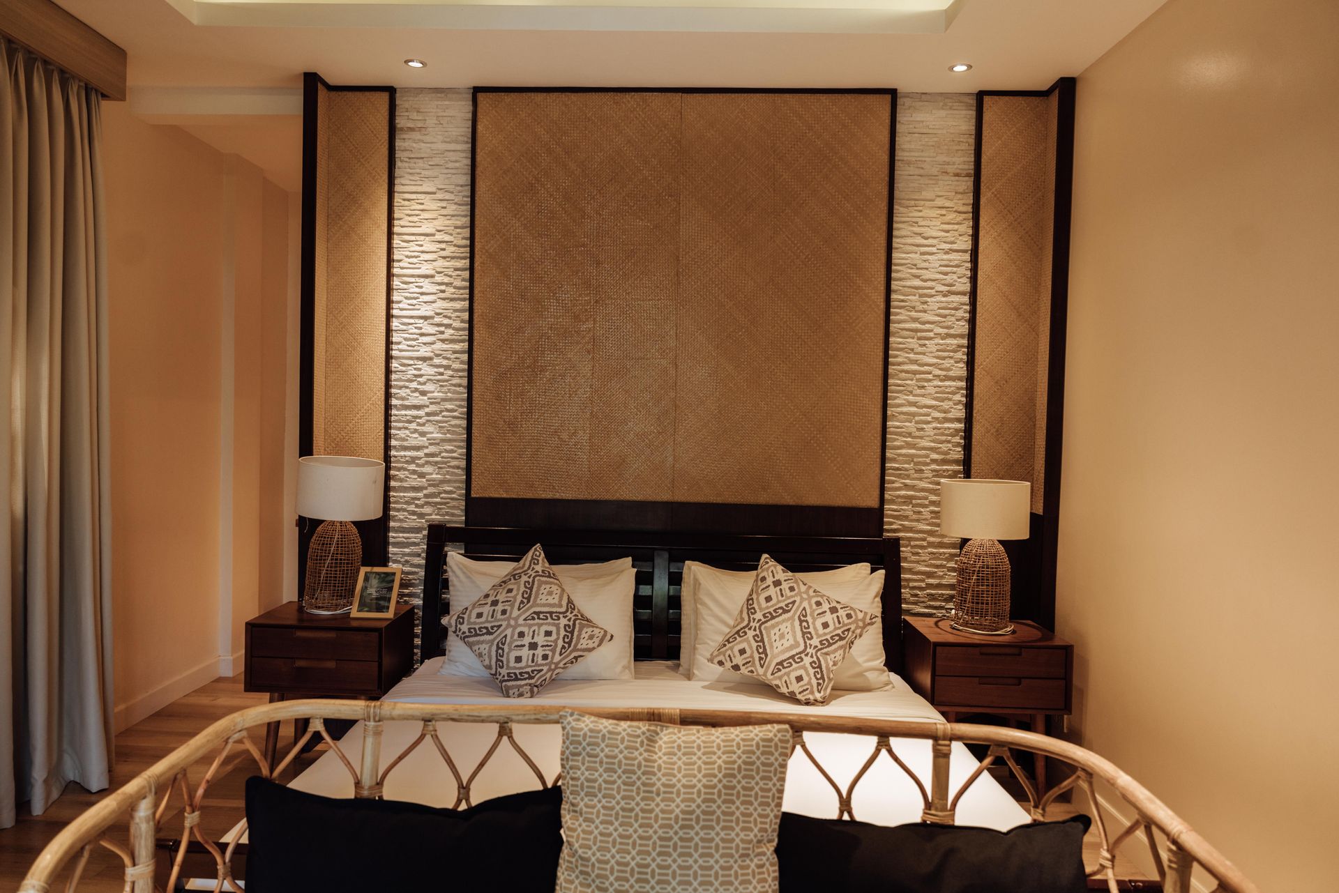 A bedroom with a large bed and a wicker chair
