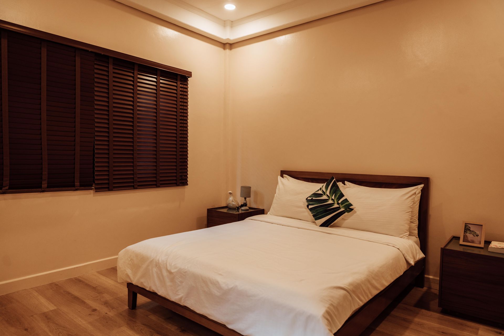 A bedroom with a bed , nightstand , and window with blinds.