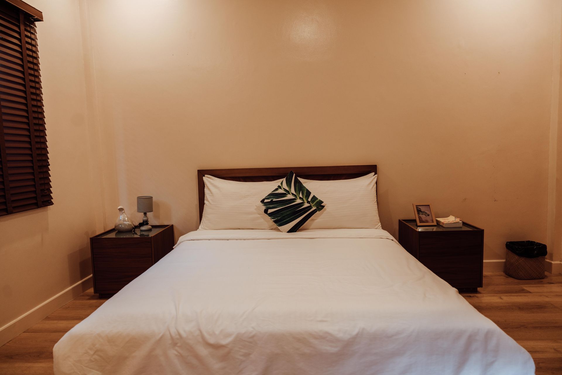 A bedroom with a bed , two nightstands and a window.