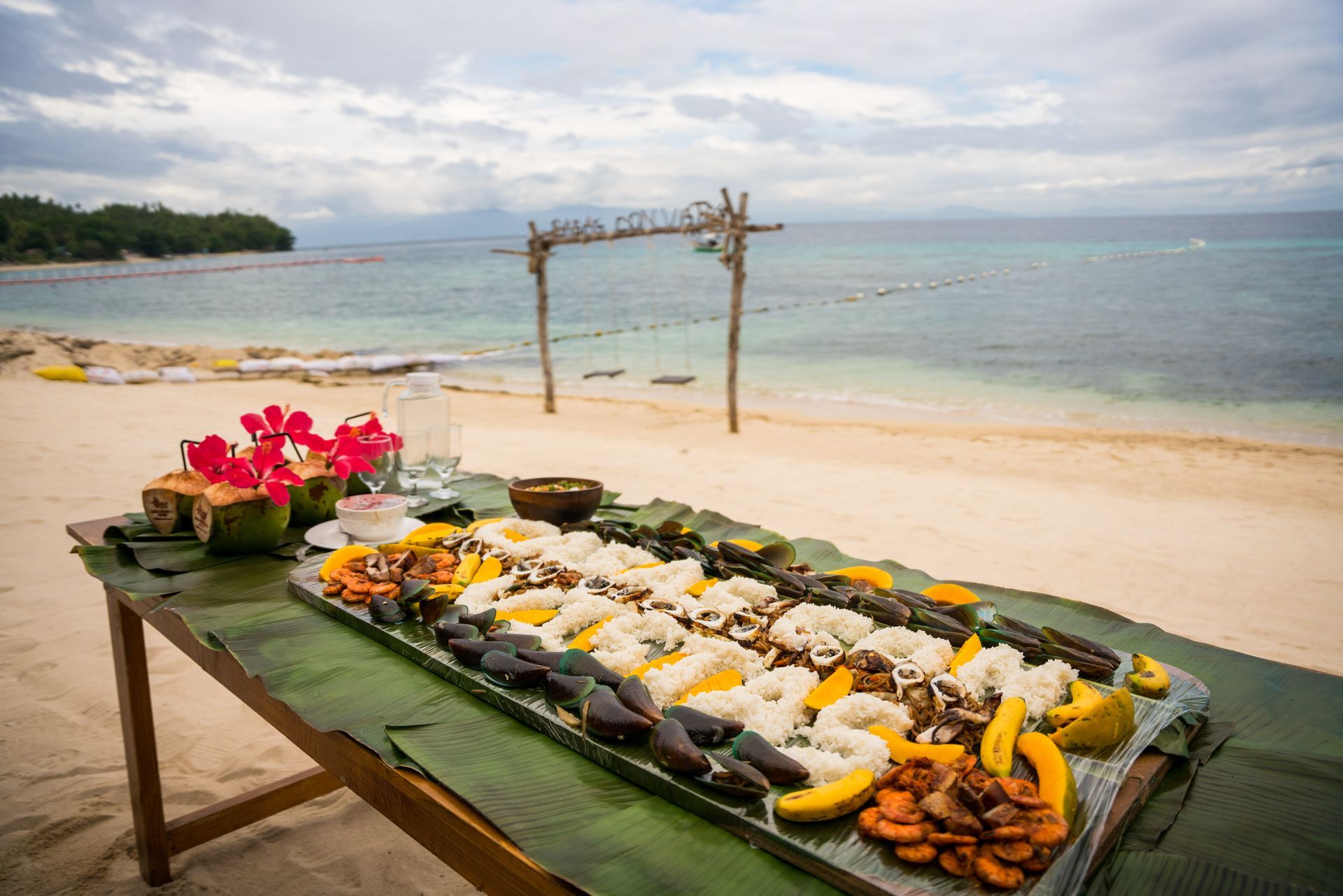 A table with a bunch of food on it on a beach.