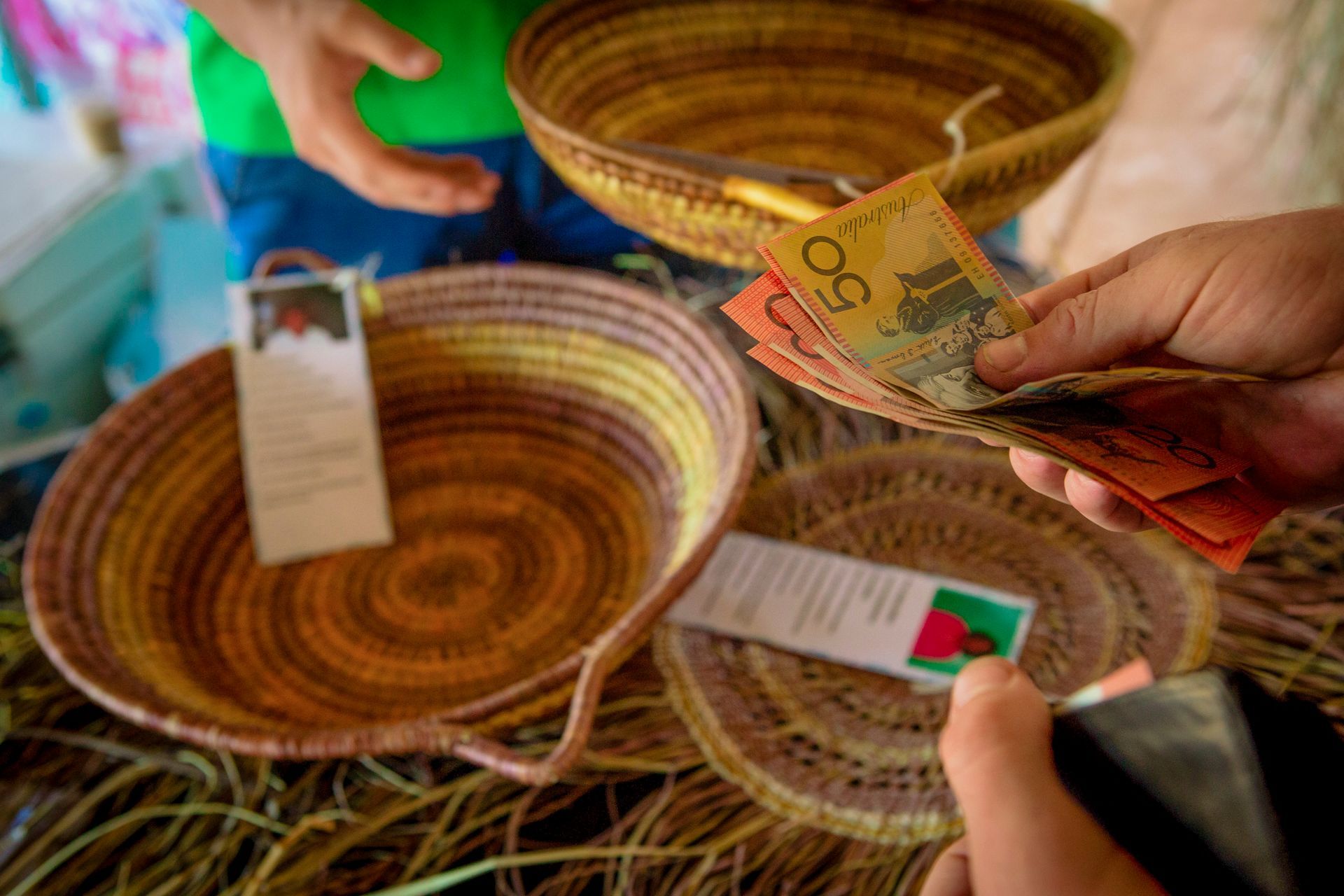 A person is holding a stack of money in front of a basket.