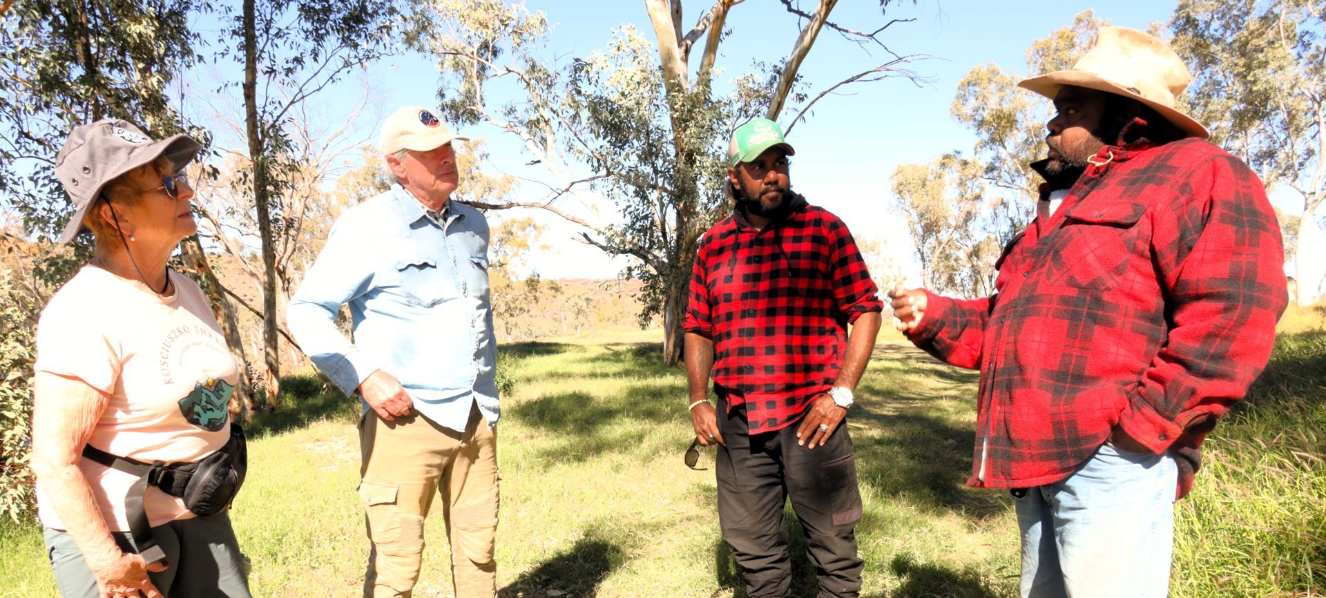 A group of people are standing in a field talking to each other.