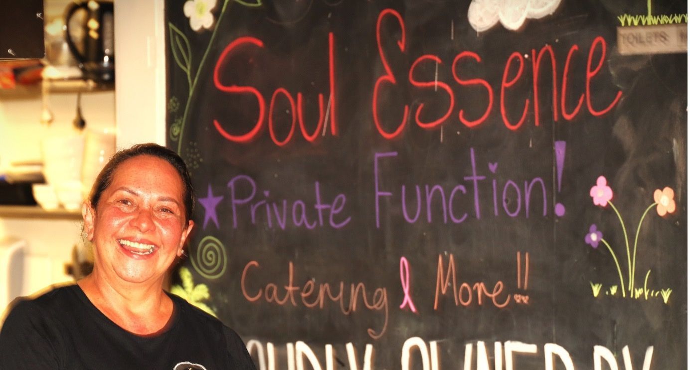 A woman stands in front of a blackboard that says soul essence