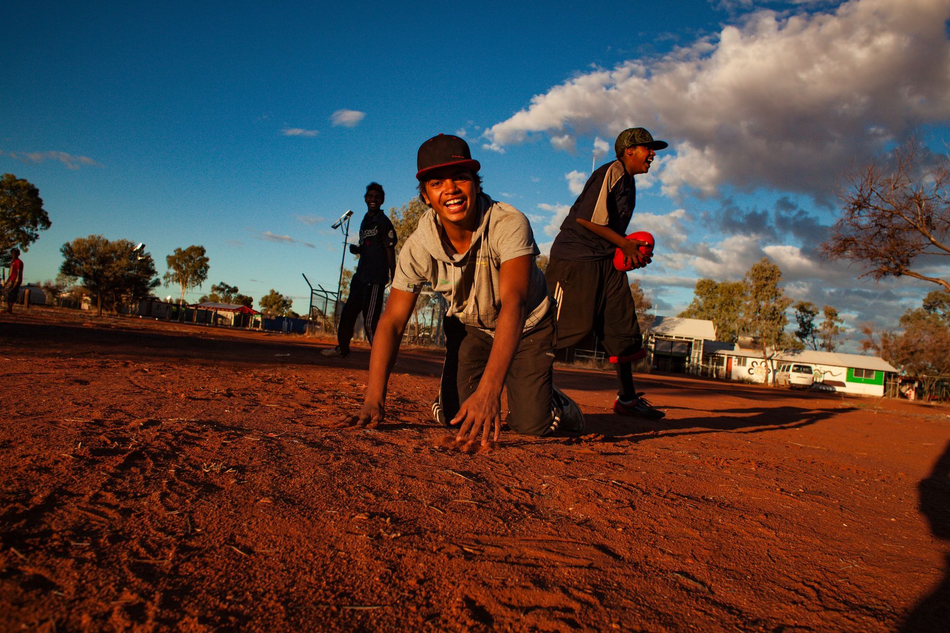 A man is kneeling on the ground in the dirt.