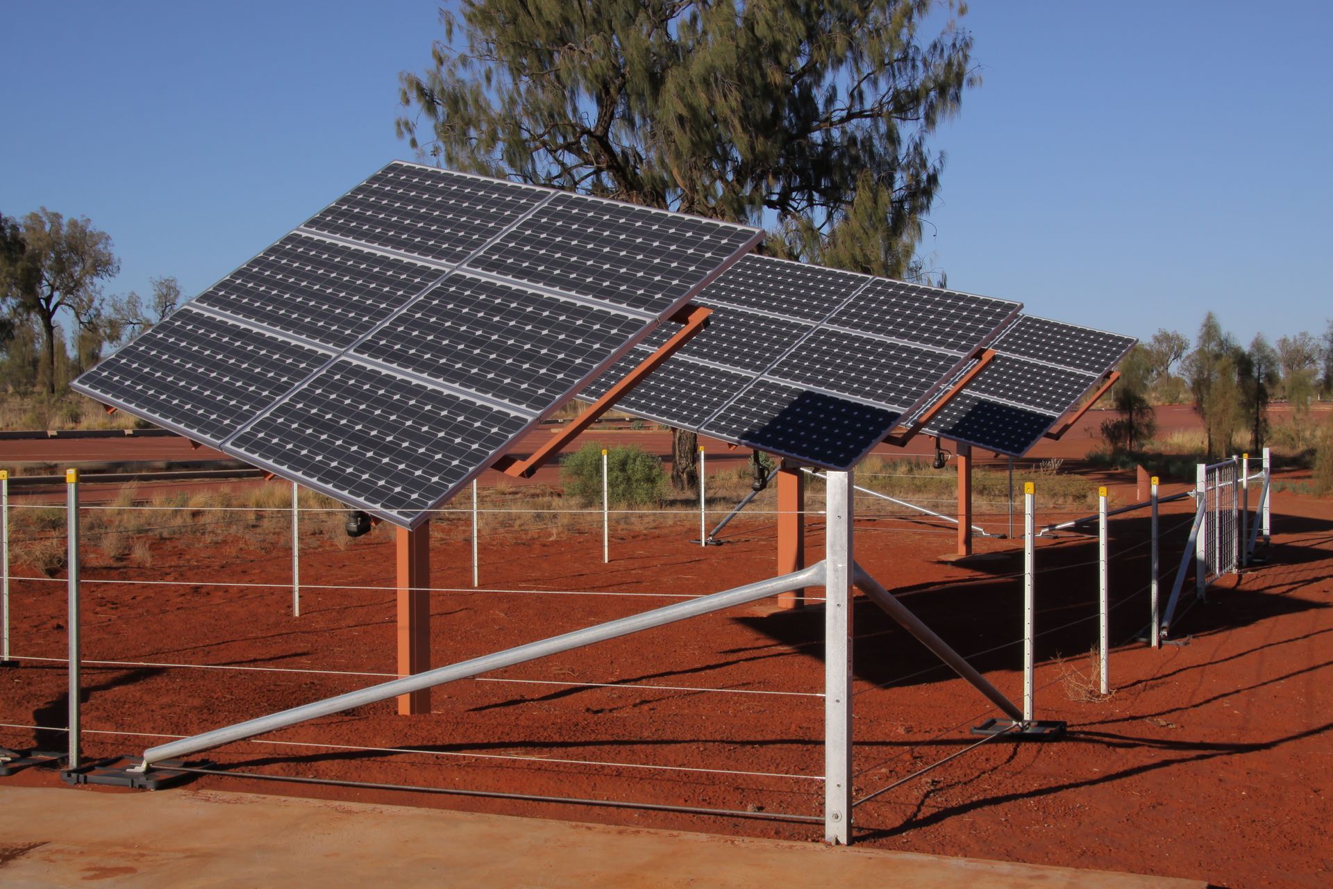 A row of solar panels sitting on top of a dirt field
