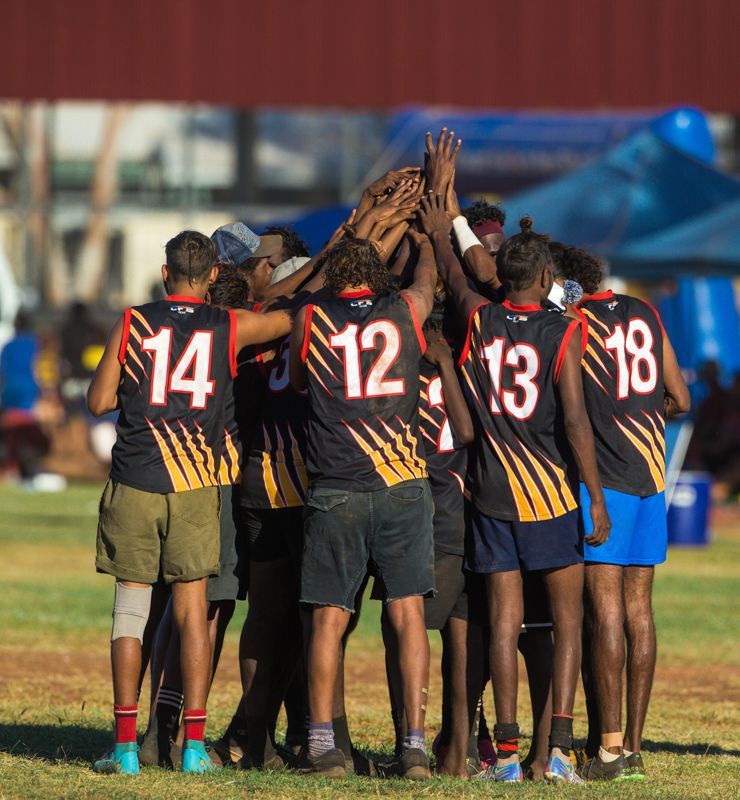 A man is kneeling on the ground in the dirt.