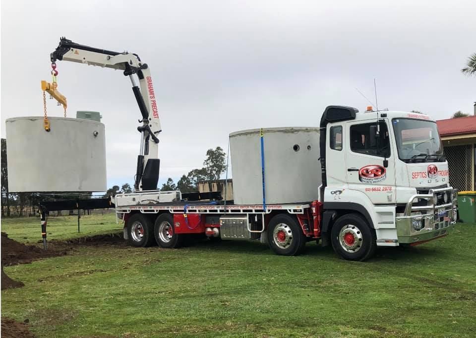 A Truck With a Crane Attached to It is a Concrete Cylinder — Graham's Precast Concrete Products Pty Ltd in Kyogle, NSW