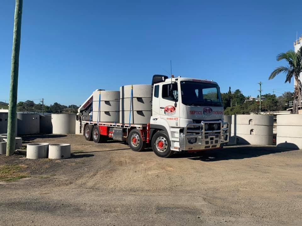 A Truck is Carrying Concrete Cylinders in a Parking Lot — Graham's Precast Concrete Products Pty Ltd in Kyogle, NSW