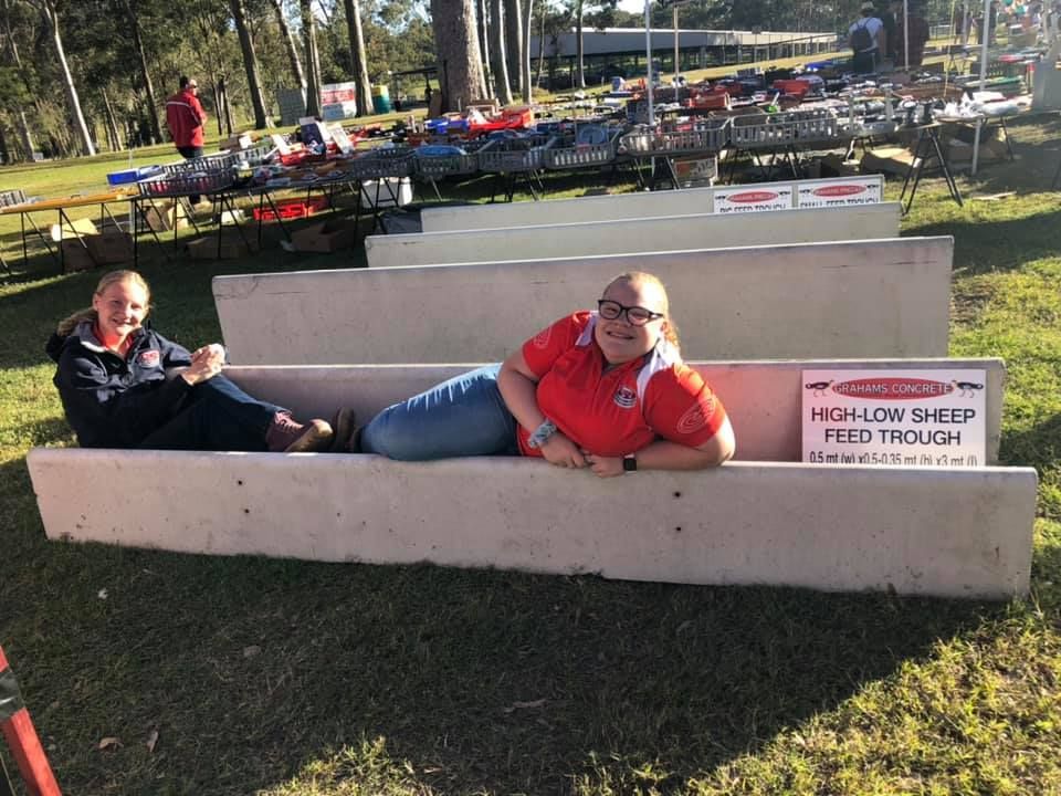Two Women Are Laying on a Feed Trough in the Grass — Graham's Precast Concrete Products Pty Ltd in Kyogle, NSW
