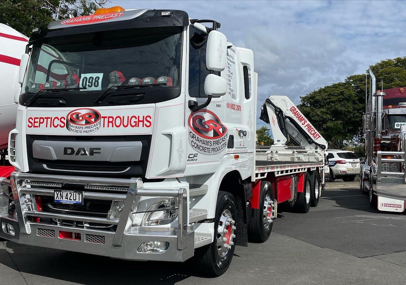 A White Truck Is Parked In A Parking Lot Next To Another Truck — Graham's Precast Concrete Products 