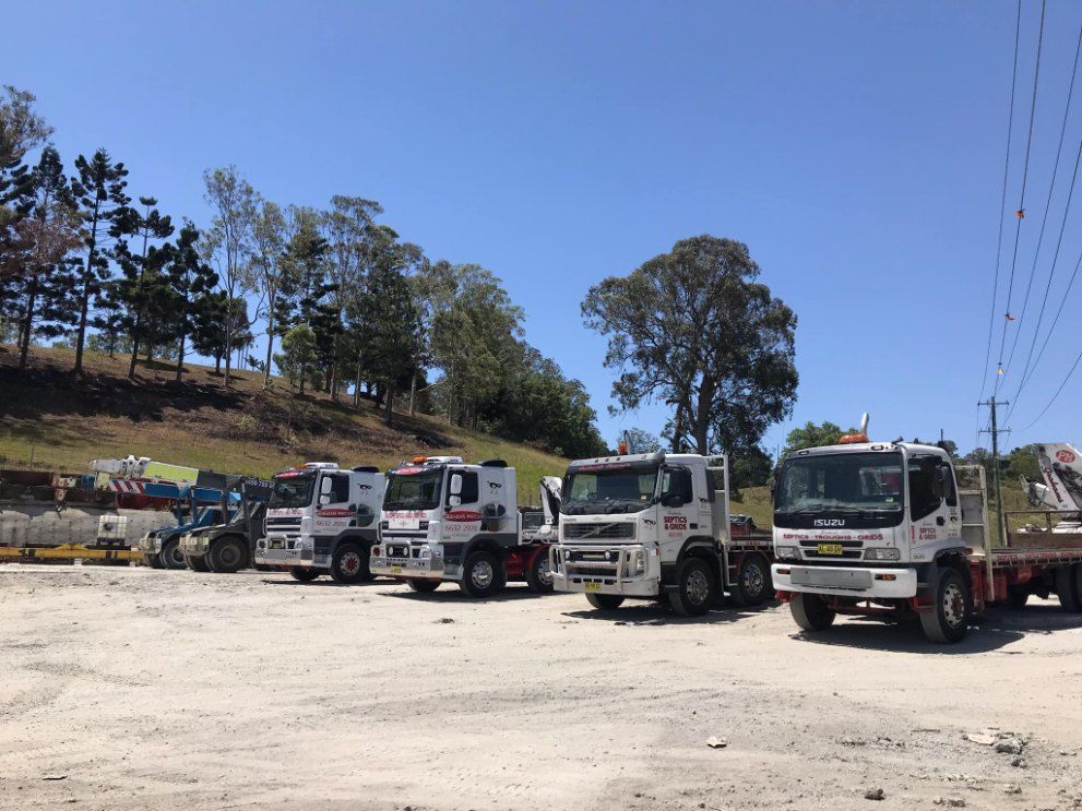 A Row of Trucks Are Parked in a Dirt Lot — Graham's Precast Concrete Products Pty Ltd in Kyogle, NSW