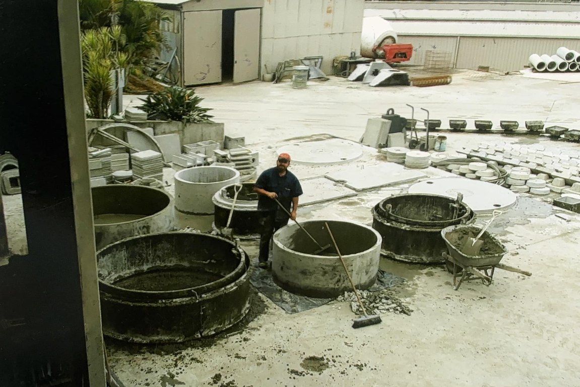 A Man is Standing in Front of a Bunch of Concrete Containers — Graham's Precast Concrete Products Pty Ltd in Kyogle, NSW