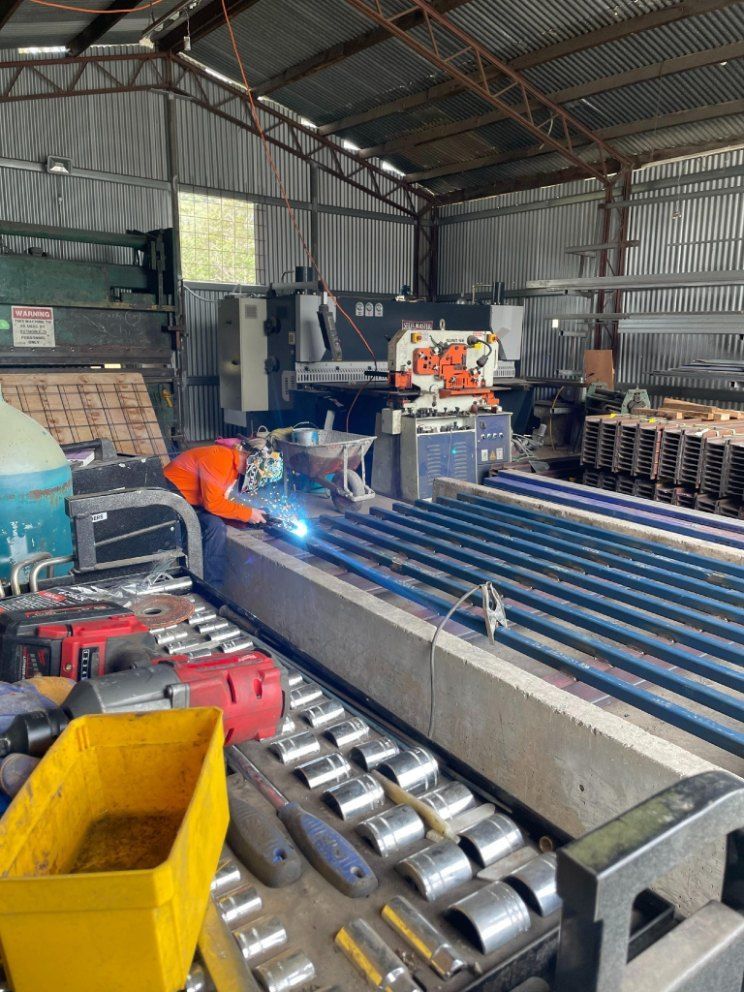 A Man is Welding a Piece of Metal in a Warehouse — Graham's Precast Concrete Products Pty Ltd in Kyogle, NSW