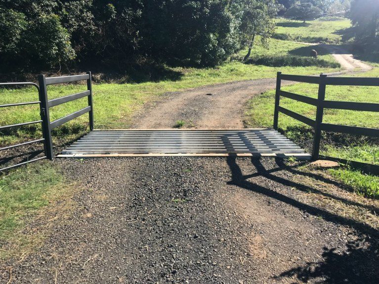 A Metal Bridge Over a Dirt Road Next to a Wooden Fence — Graham's Precast Concrete Products Pty Ltd in Kyogle, NSW