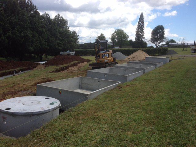 A Row of Concrete Tanks Are Lined Up in a Grassy Field — Graham's Precast Concrete Products Pty Ltd in Kyogle, NSW