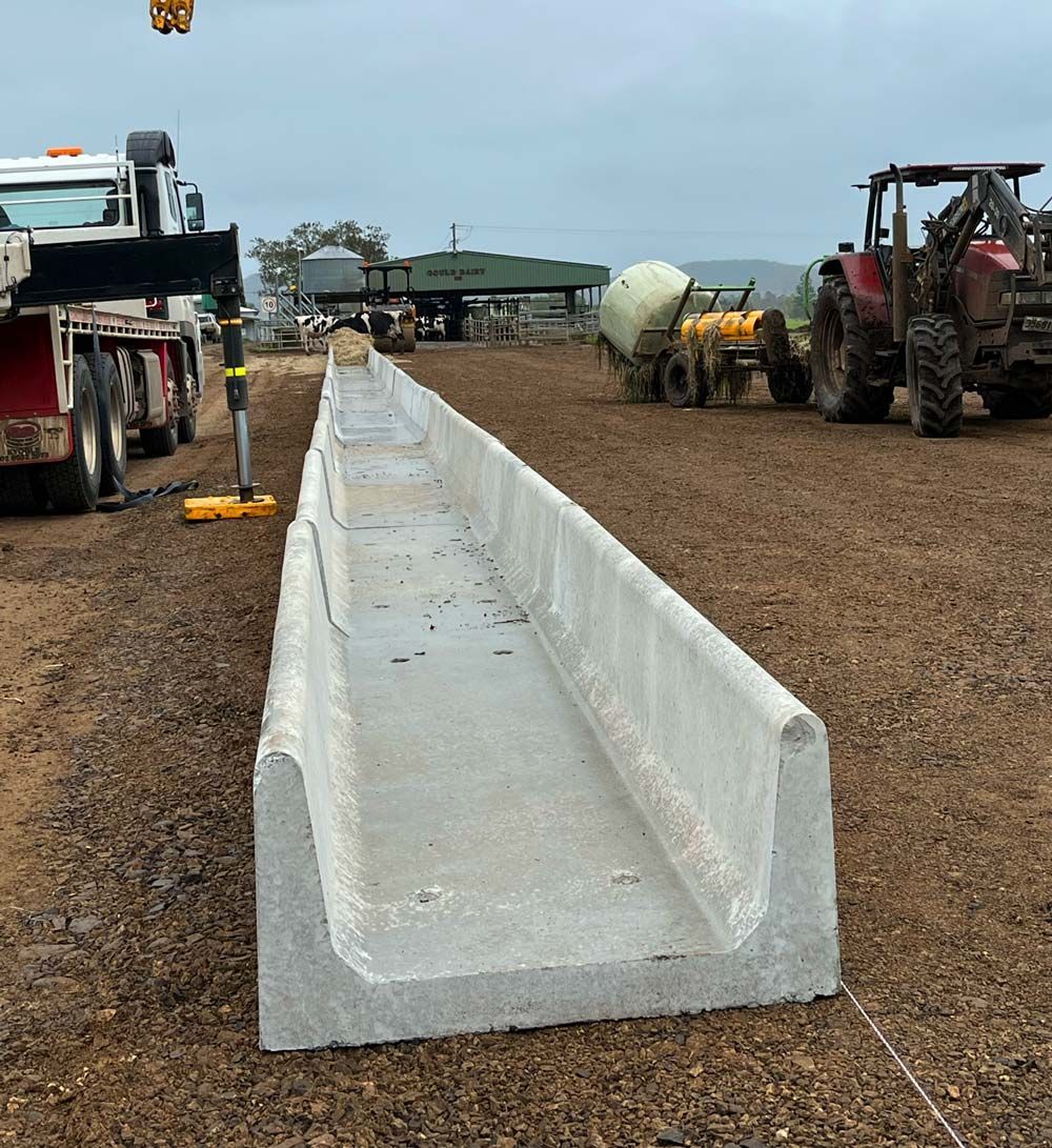 A Long Concrete Beam is Sitting in the Middle of a Dirt Field — Graham's Precast Concrete Products Pty Ltd in Kyogle, NSW