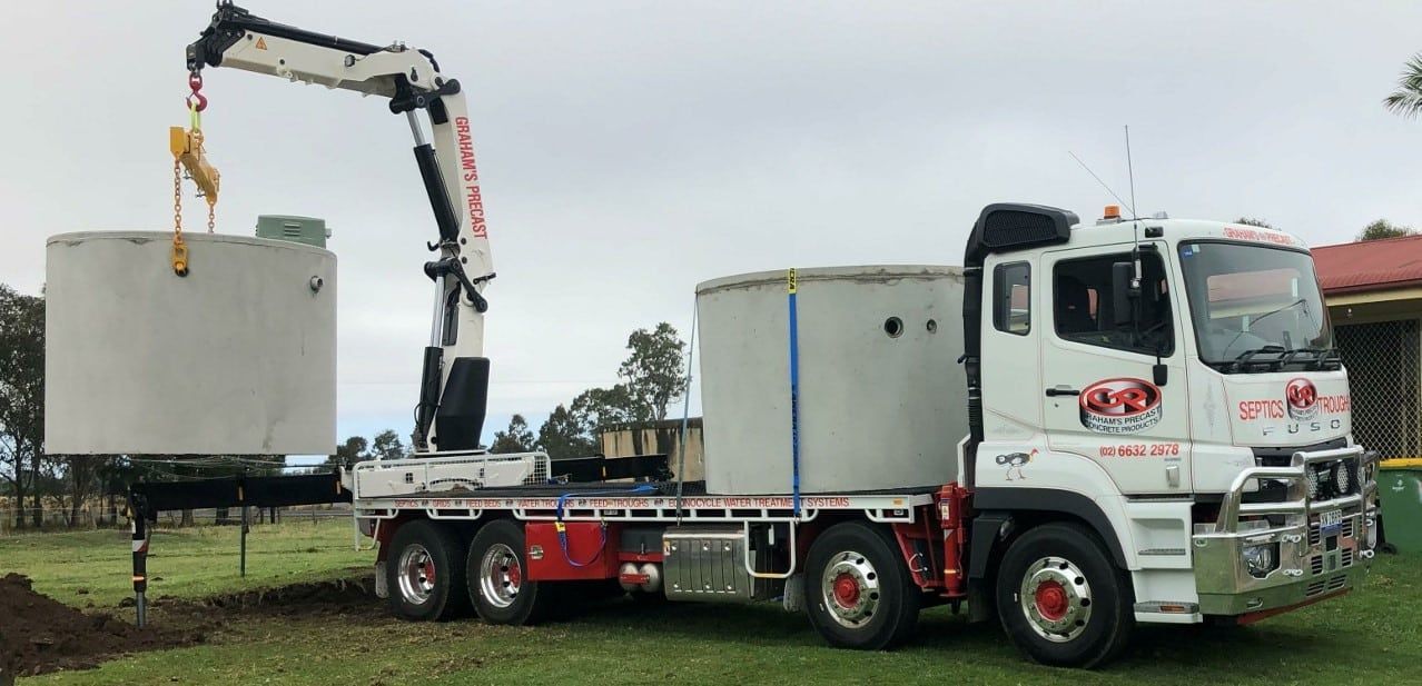 A Truck With a Crane Attached to It is a Concrete Cylinder — Graham's Precast Concrete Products Pty Ltd in Kyogle, NSW