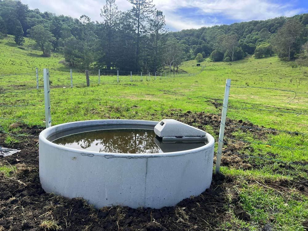 A Large Concrete Pool Filled With Water in a Grassy Field — Graham's Precast Concrete Products Pty Ltd in Kyogle, NSW