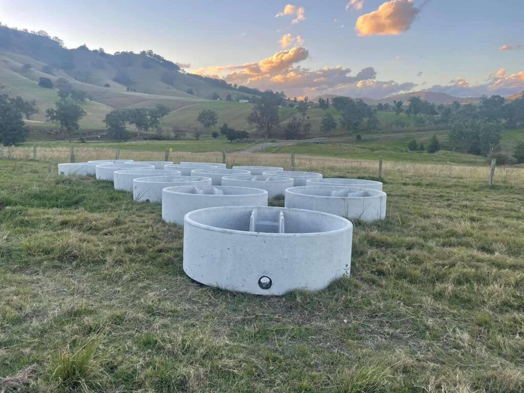 A Row of Concrete Rings Are Sitting in a Grassy Field — Graham's Precast Concrete Products Pty Ltd in Kyogle, NSW