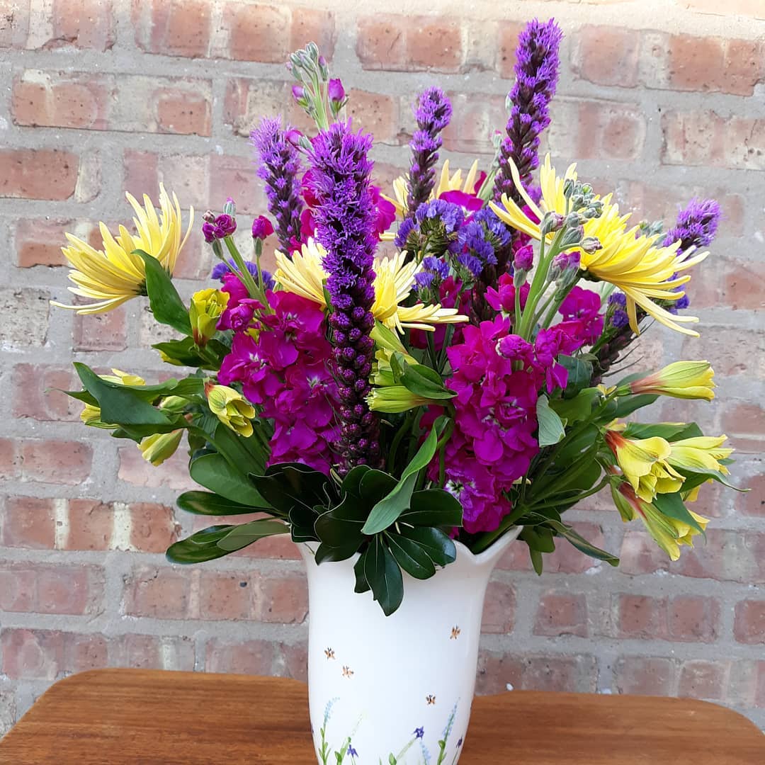 A white vase filled with purple and yellow flowers