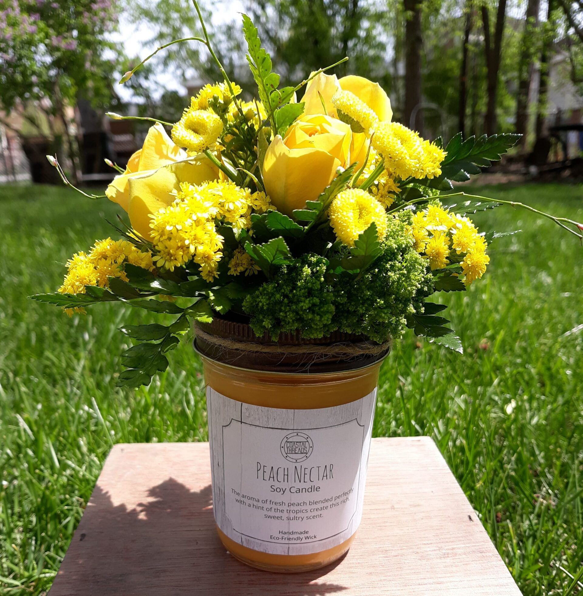 A jar of peach nectar with yellow flowers in it