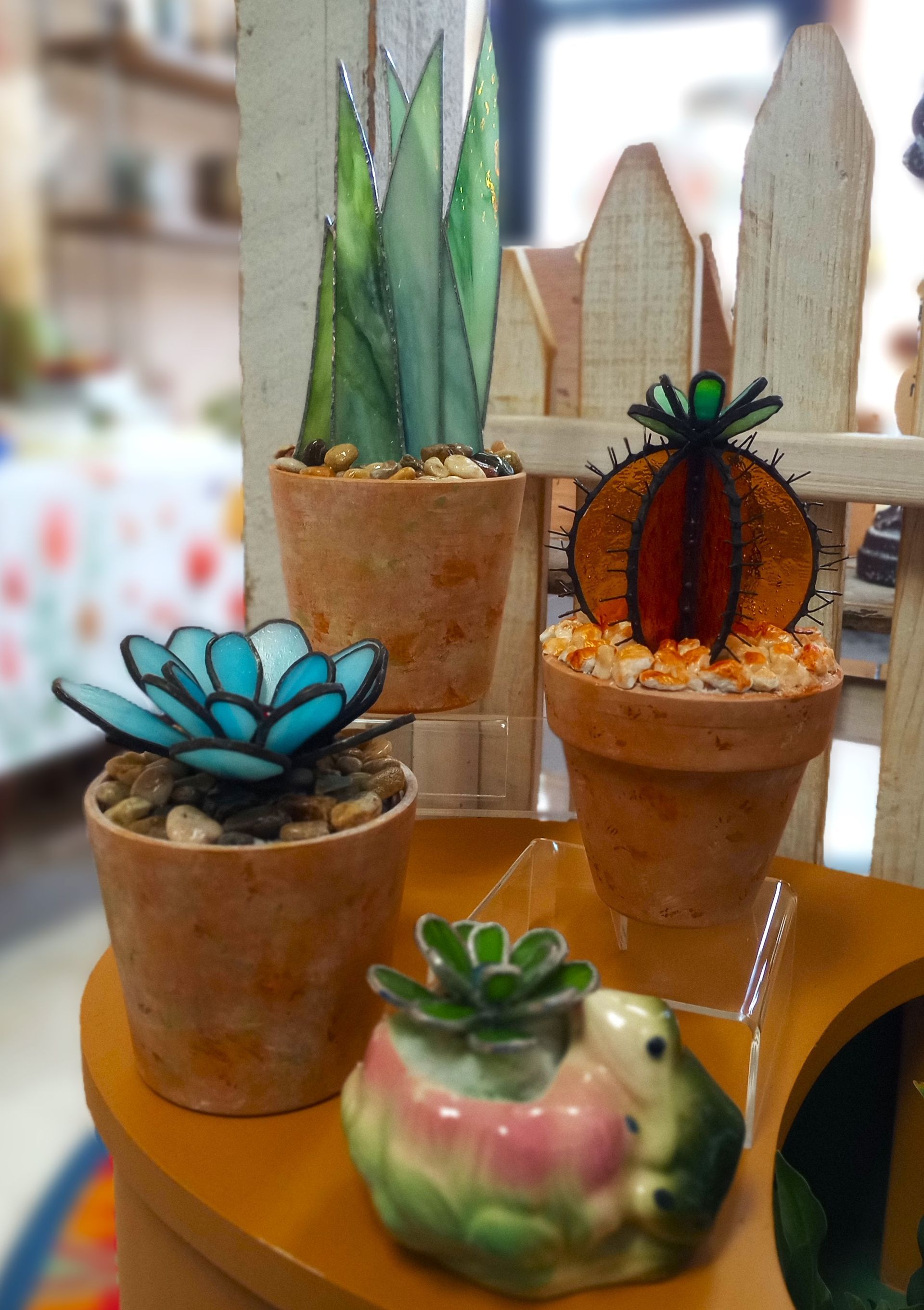 Three potted plants and a frog on a table