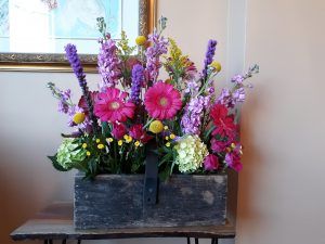 A wooden box filled with flowers is sitting on a table.