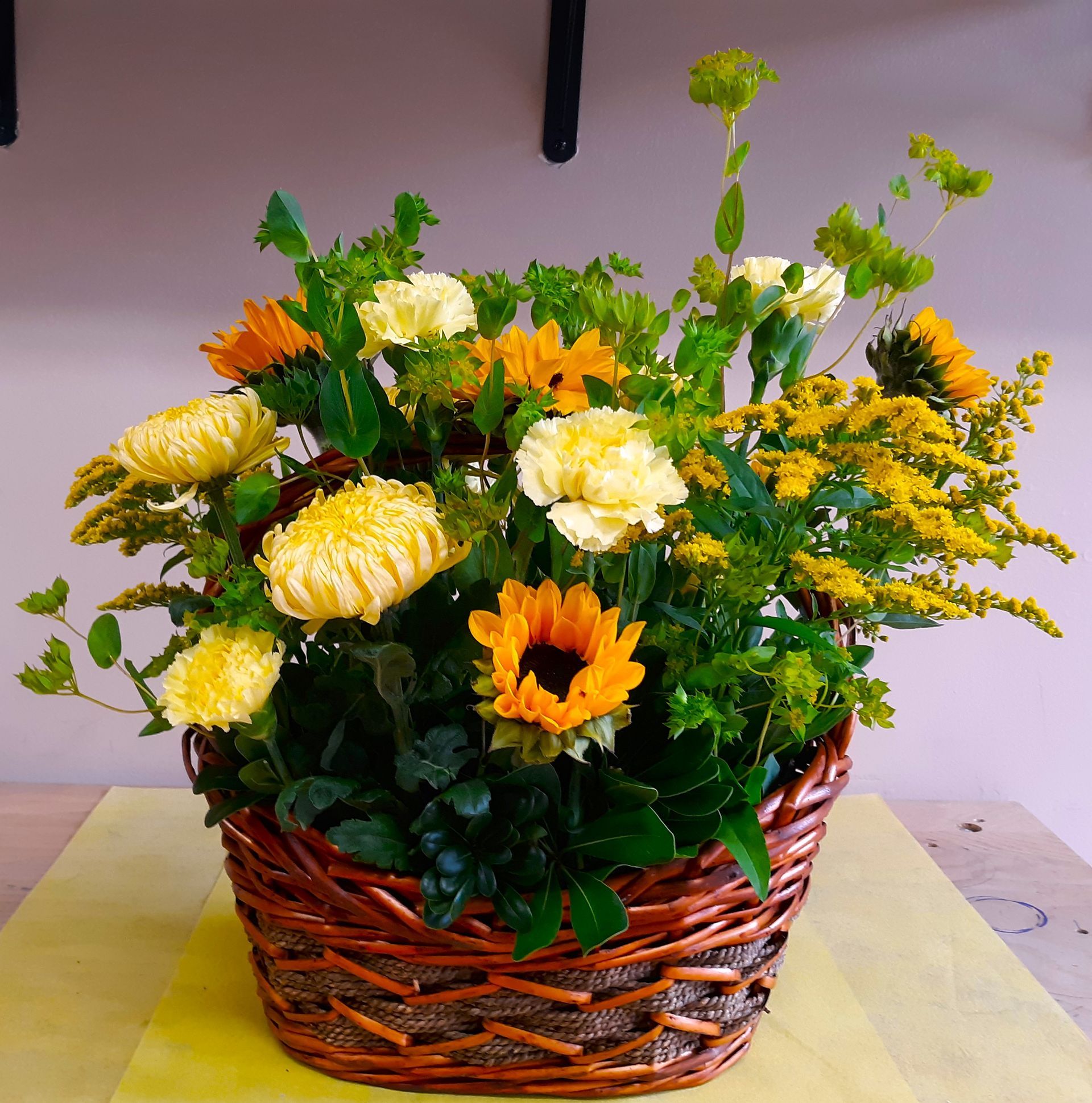 A wicker basket filled with yellow and orange flowers