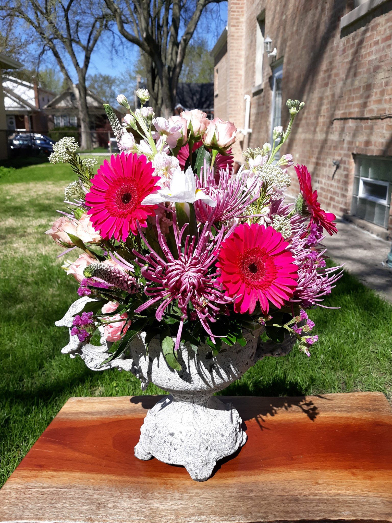 A vase filled with pink and purple flowers is sitting on a wooden table.