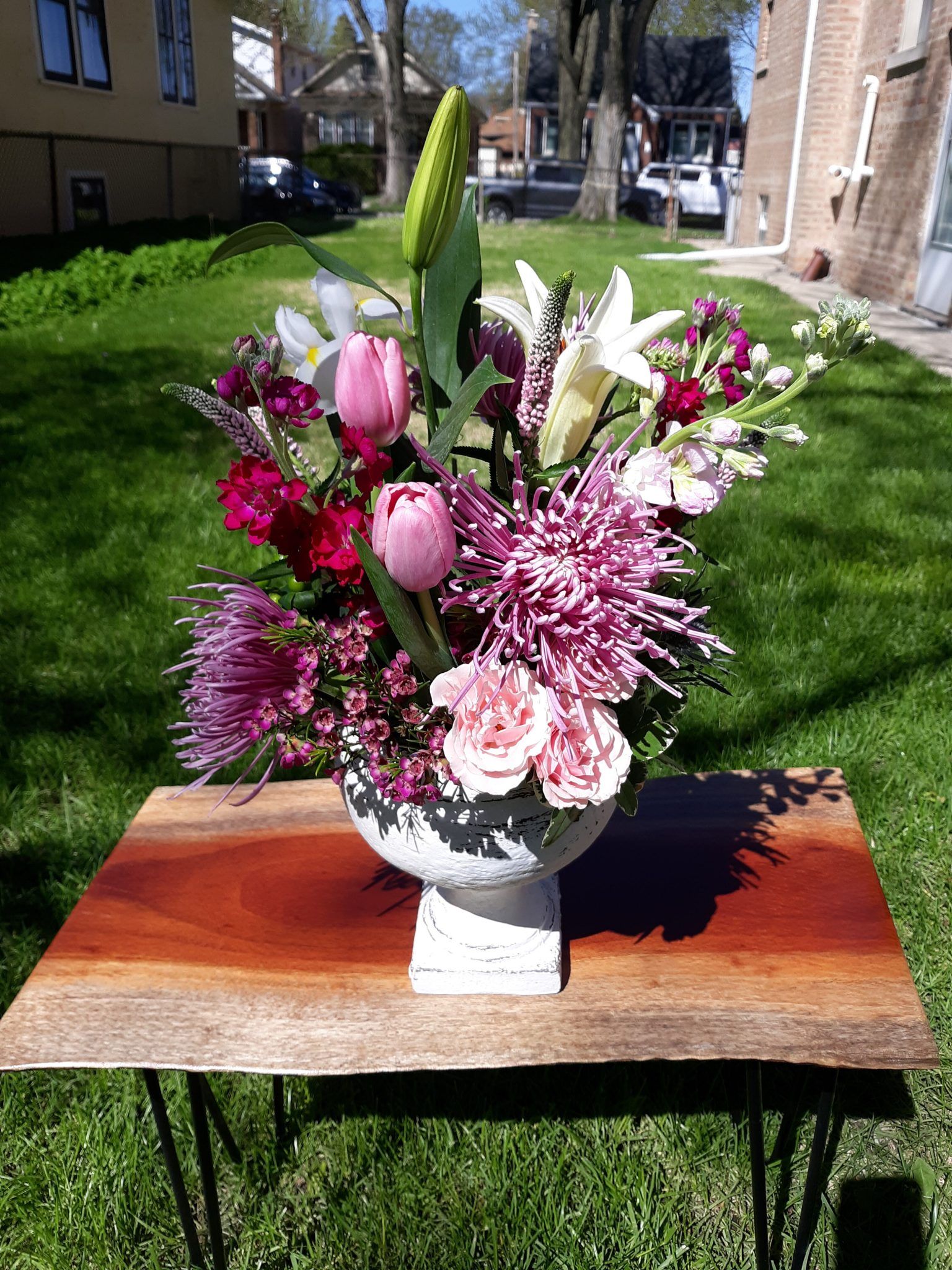 A vase filled with pink and purple flowers is sitting on a wooden table.