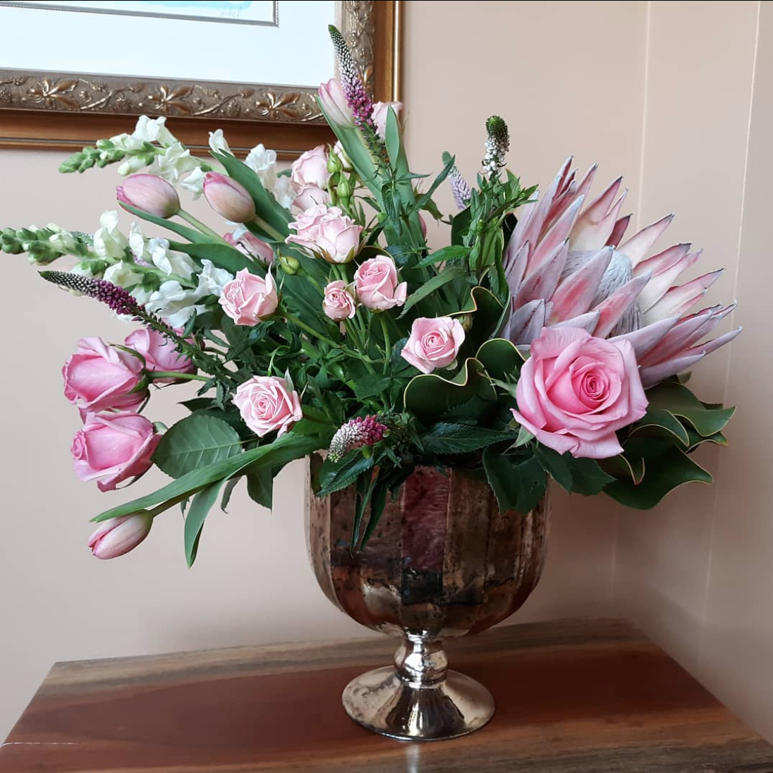 A vase filled with pink roses and other flowers
