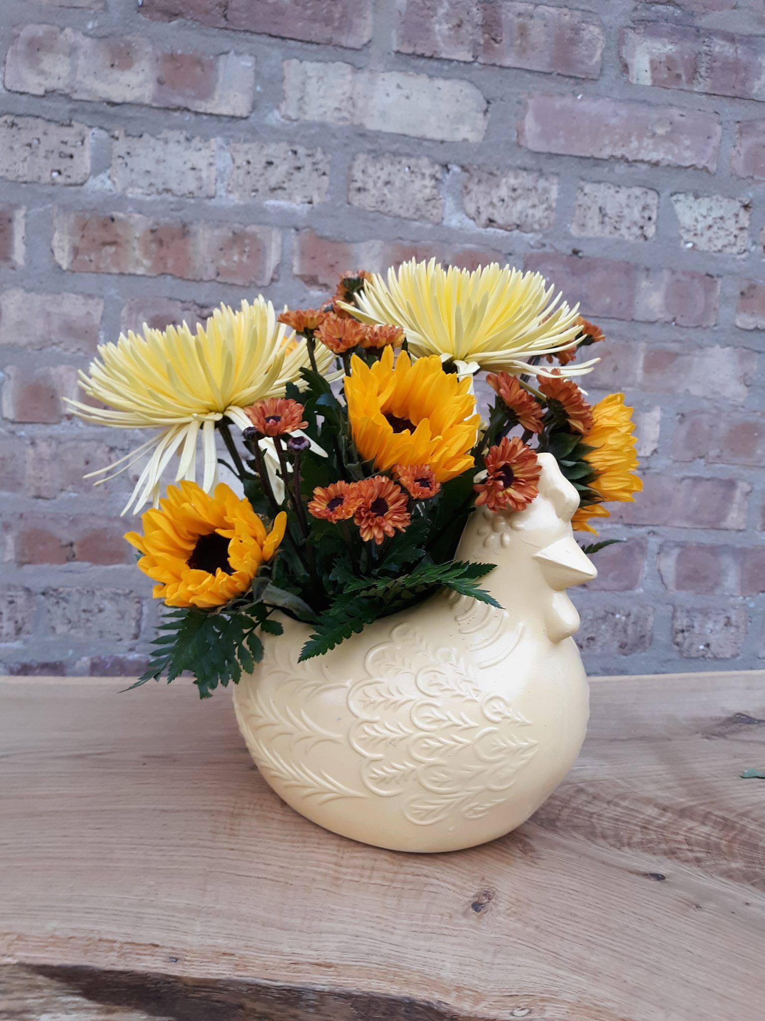 A vase filled with yellow flowers is sitting on a wooden table.
