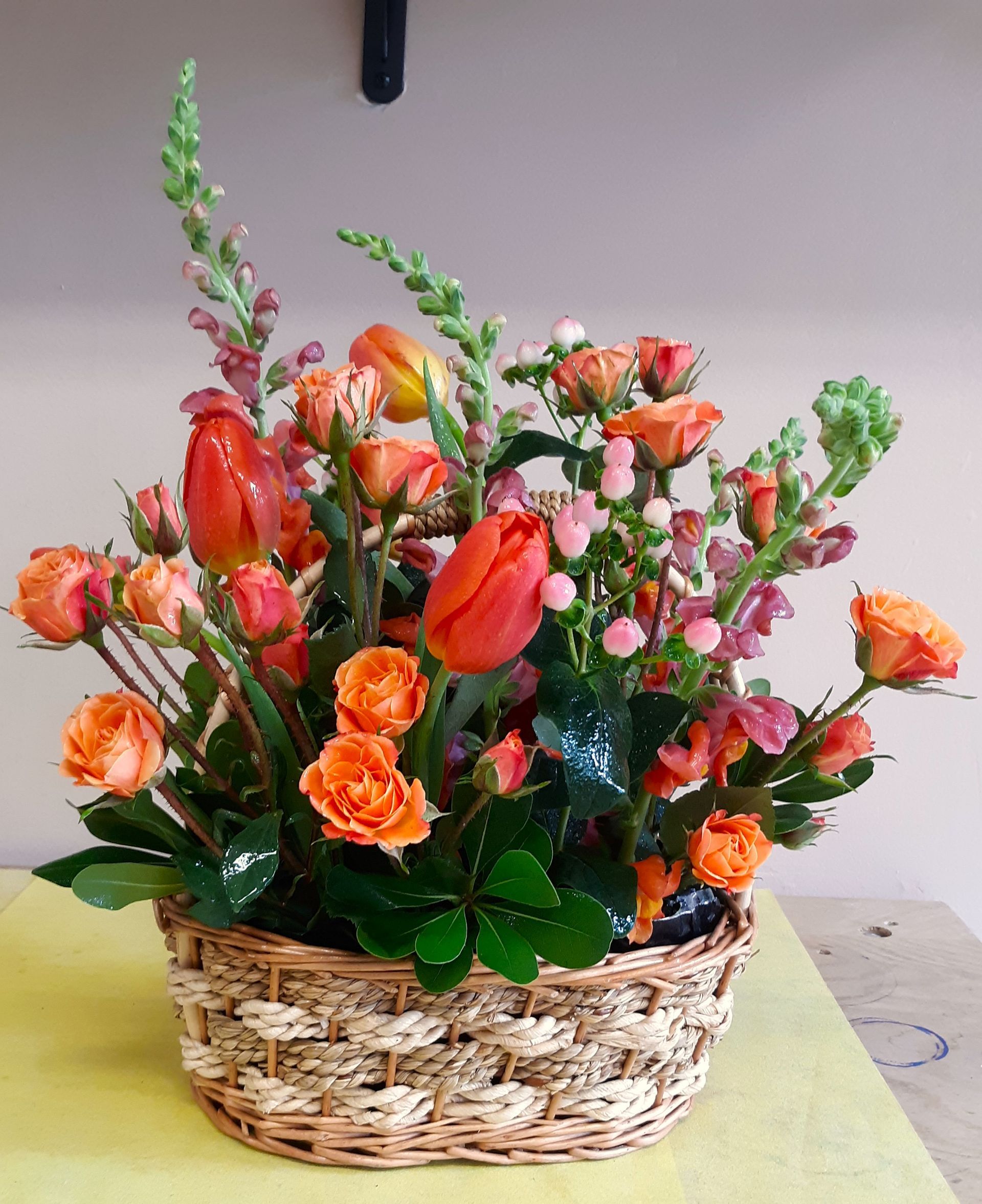 A wicker basket filled with orange flowers and greenery