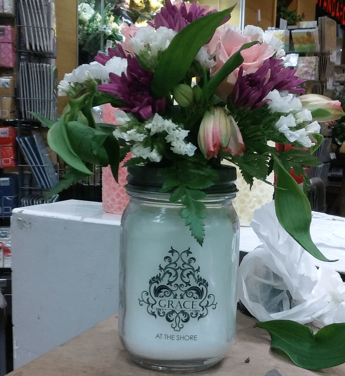 A mason jar filled with flowers sits on a table