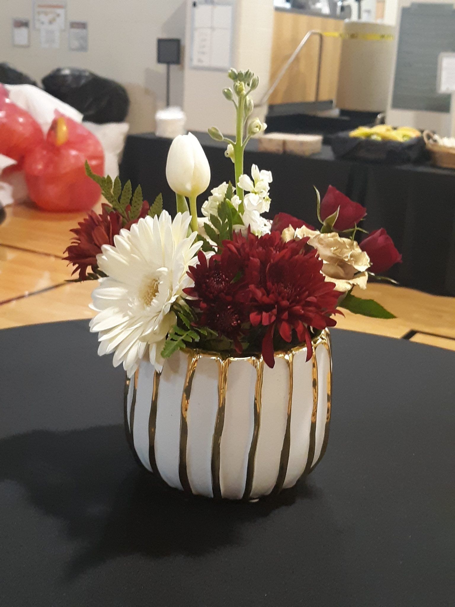 A white and gold vase filled with flowers on a table