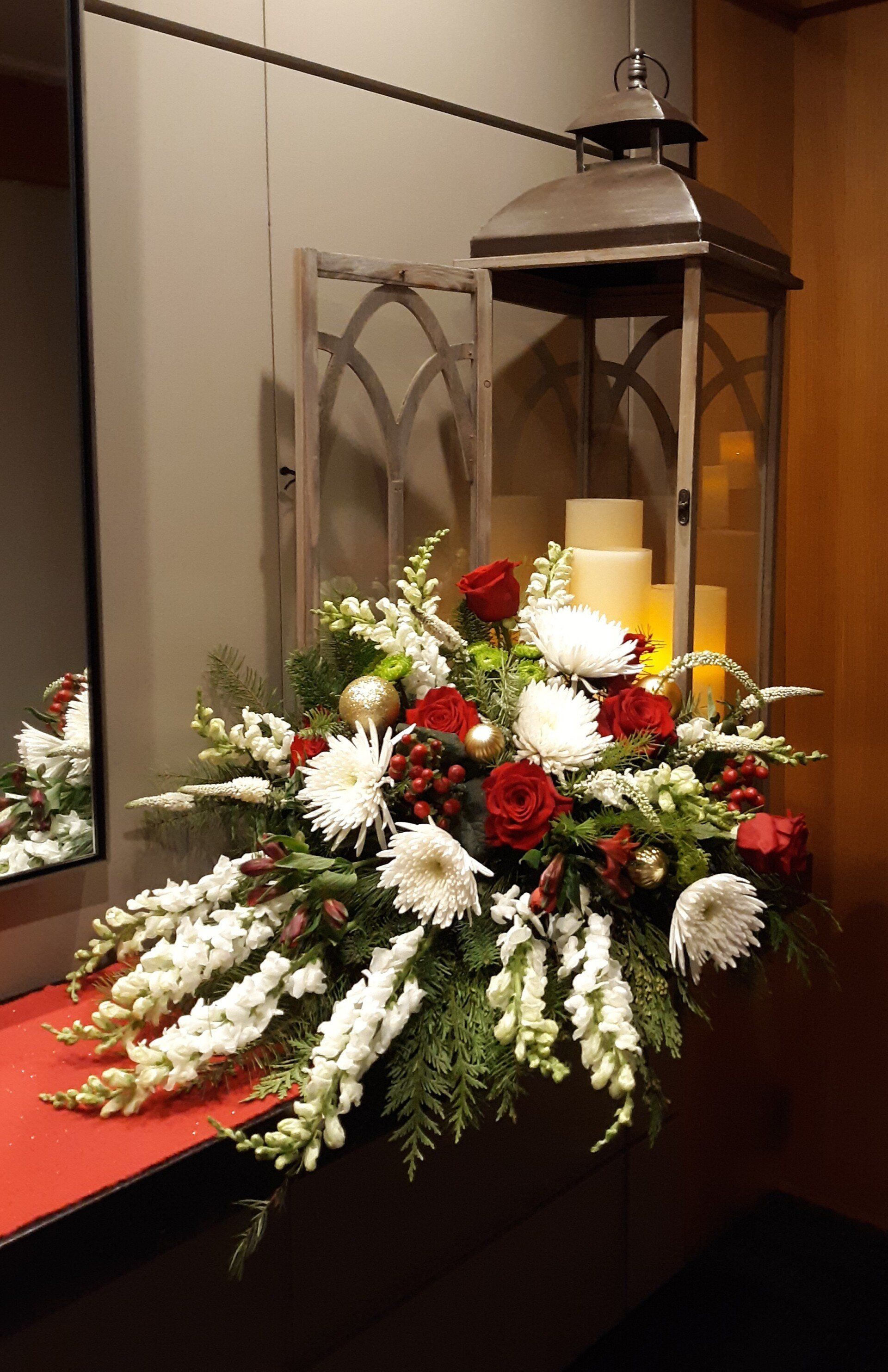A lantern filled with candles and flowers is sitting on a table next to a mirror.