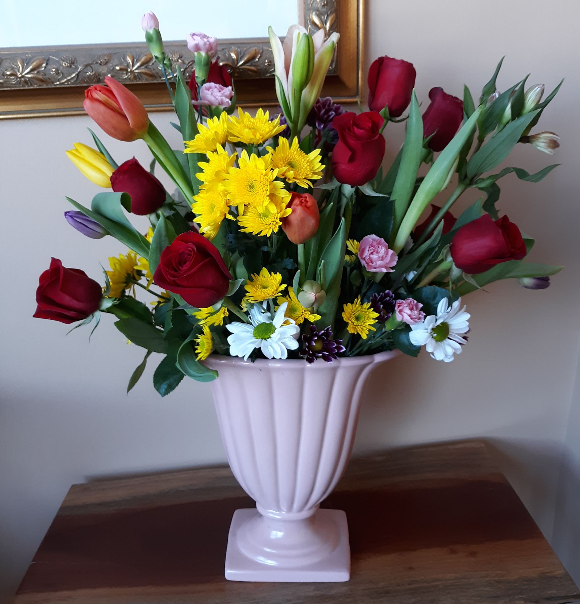 A pink vase filled with flowers sits on a table