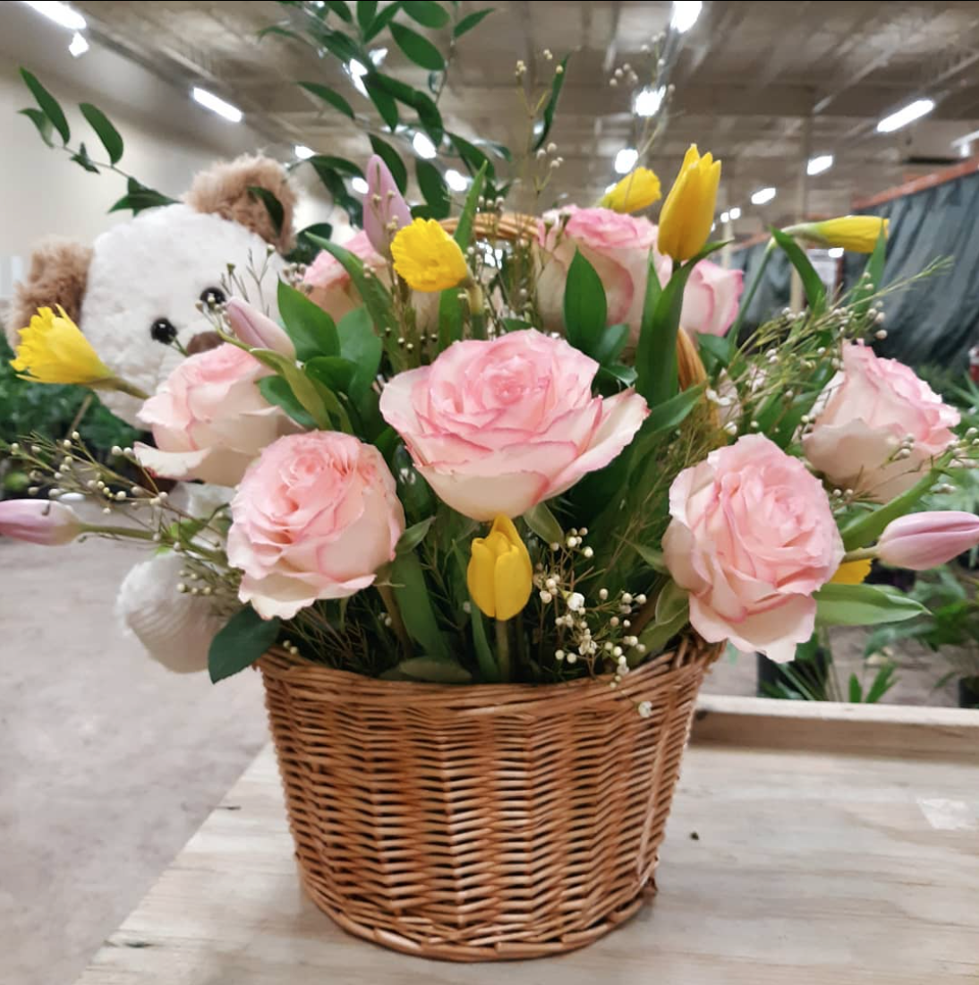 A basket filled with pink roses and yellow tulips