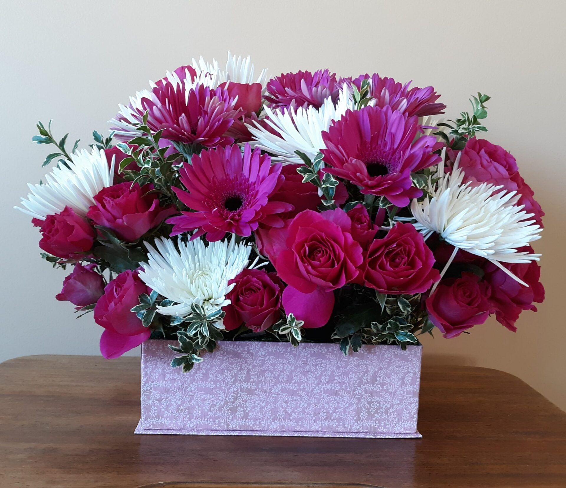 A pink box filled with pink and white flowers