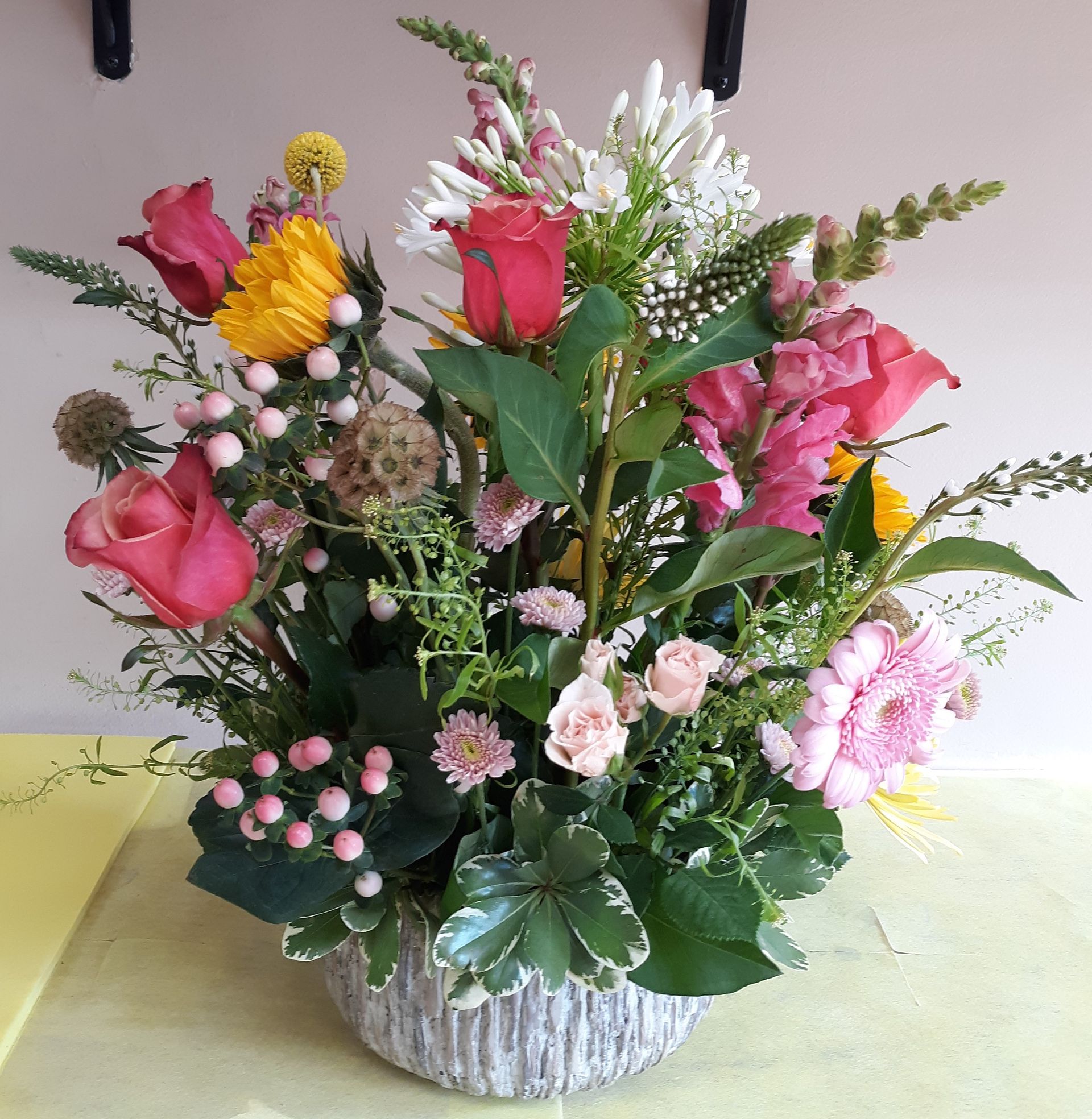 A basket filled with pink and yellow flowers sits on a table