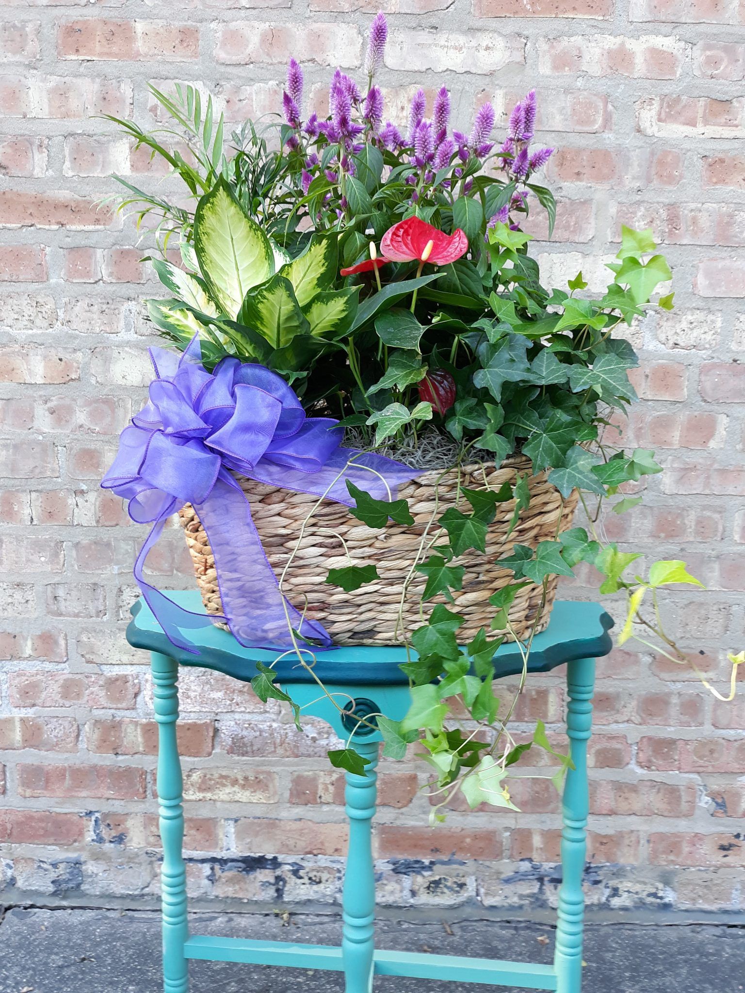 A basket filled with flowers and plants is sitting on a blue table.